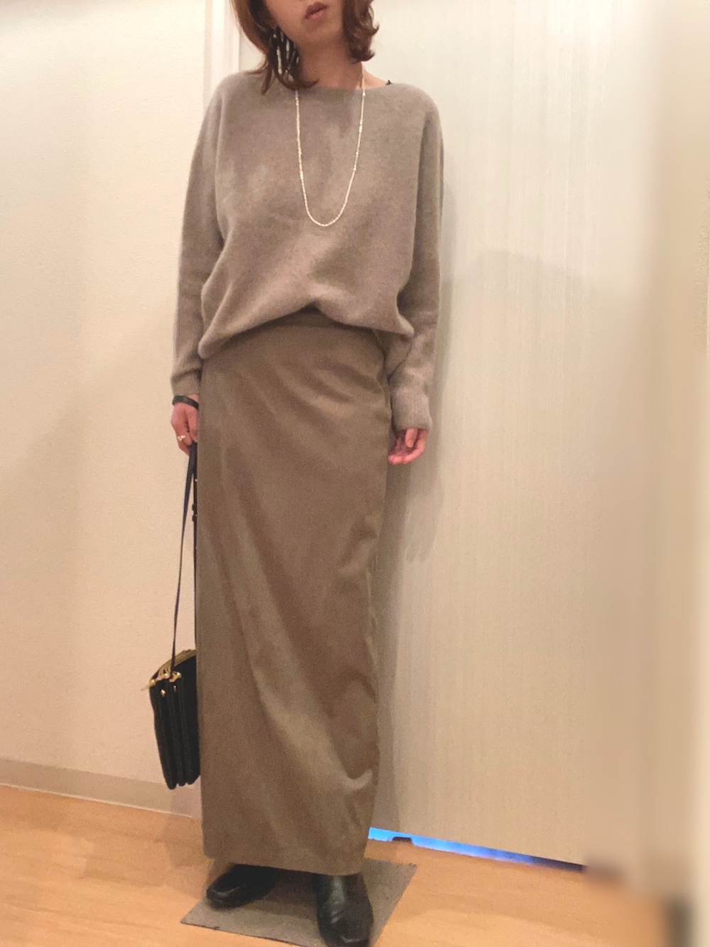 ブラウン系のニット/セーター、その他のスカート、ブラック系のブーツを着用したレディースの春コーディネートの2枚目の写真