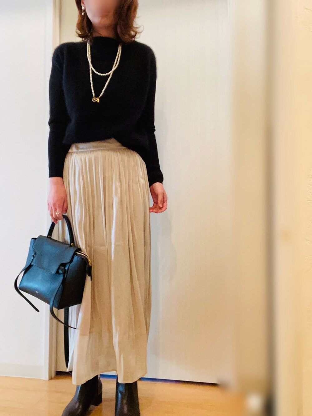 ブラック系のニット/セーター、ホワイト系のスカート、ブラウン系のブーツを着用したレディースの冬コーディネートの2枚目の写真