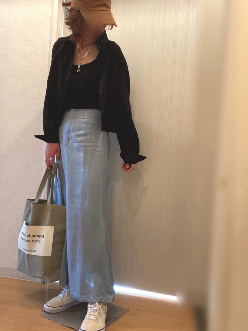 ブルー系のスカート、ホワイト系のスニーカー、グリーン系のトートバッグを着用したレディースの夏コーディネートの2枚目の写真