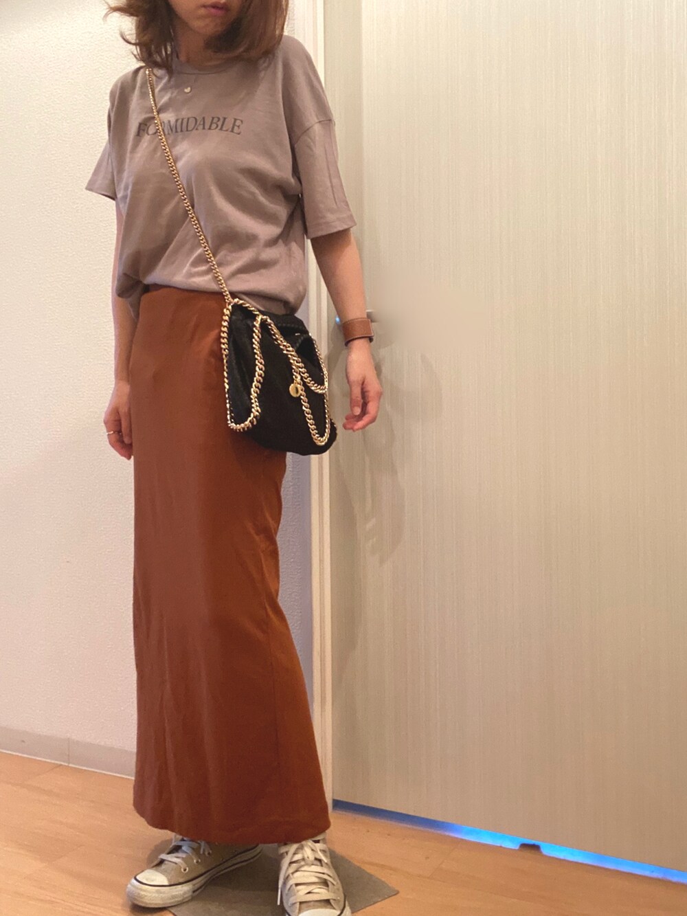 グレー系のTシャツ/カットソー、ブラウン系のスカート、ベージュ系のスニーカーを着用したレディースの秋コーディネートの2枚目の写真