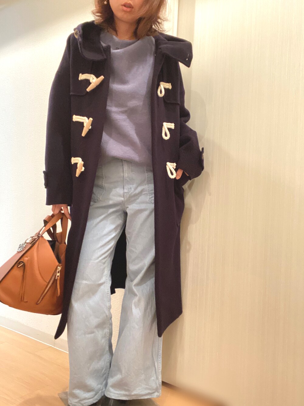 ブルー系のニット/セーター、ブルー系のデニムパンツ、ブラウン系のハンドバッグを着用したレディースの冬コーディネートの3枚目の写真