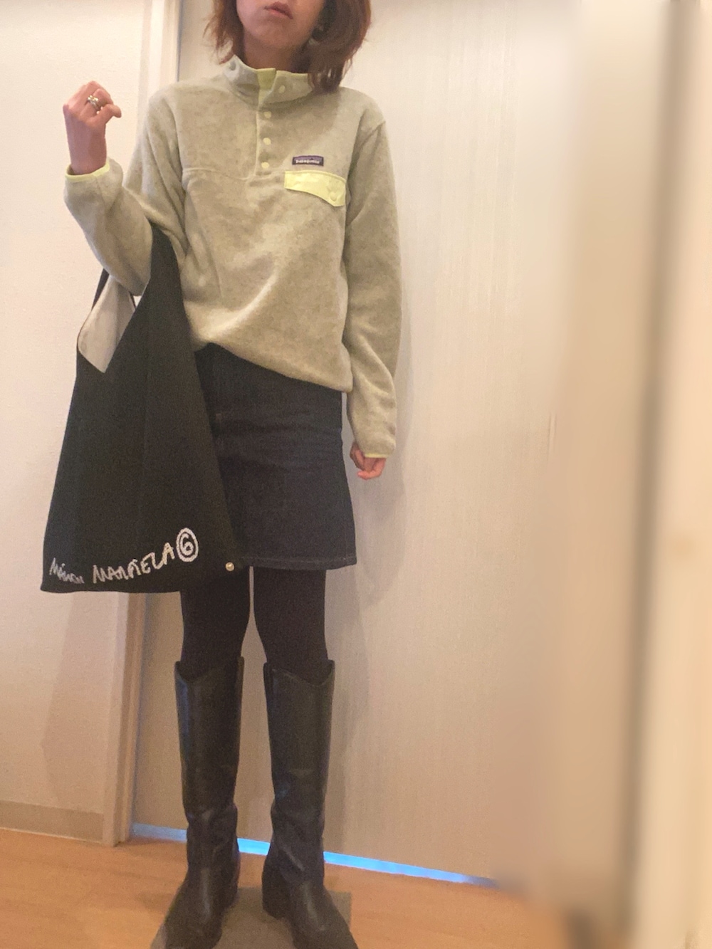 イエロー系のトップス、ブルー系のデニムスカート、ブラック系のハンドバッグを着用したレディースの冬コーディネートの2枚目の写真