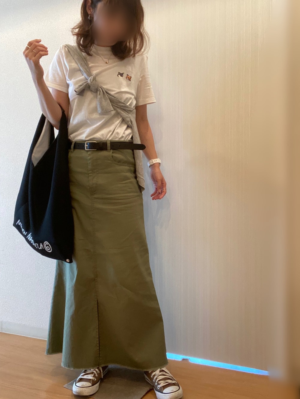 ホワイト系のTシャツ/カットソー、グリーン系のスカート、ブラック系のハンドバッグを着用したレディースの秋コーディネートの2枚目の写真