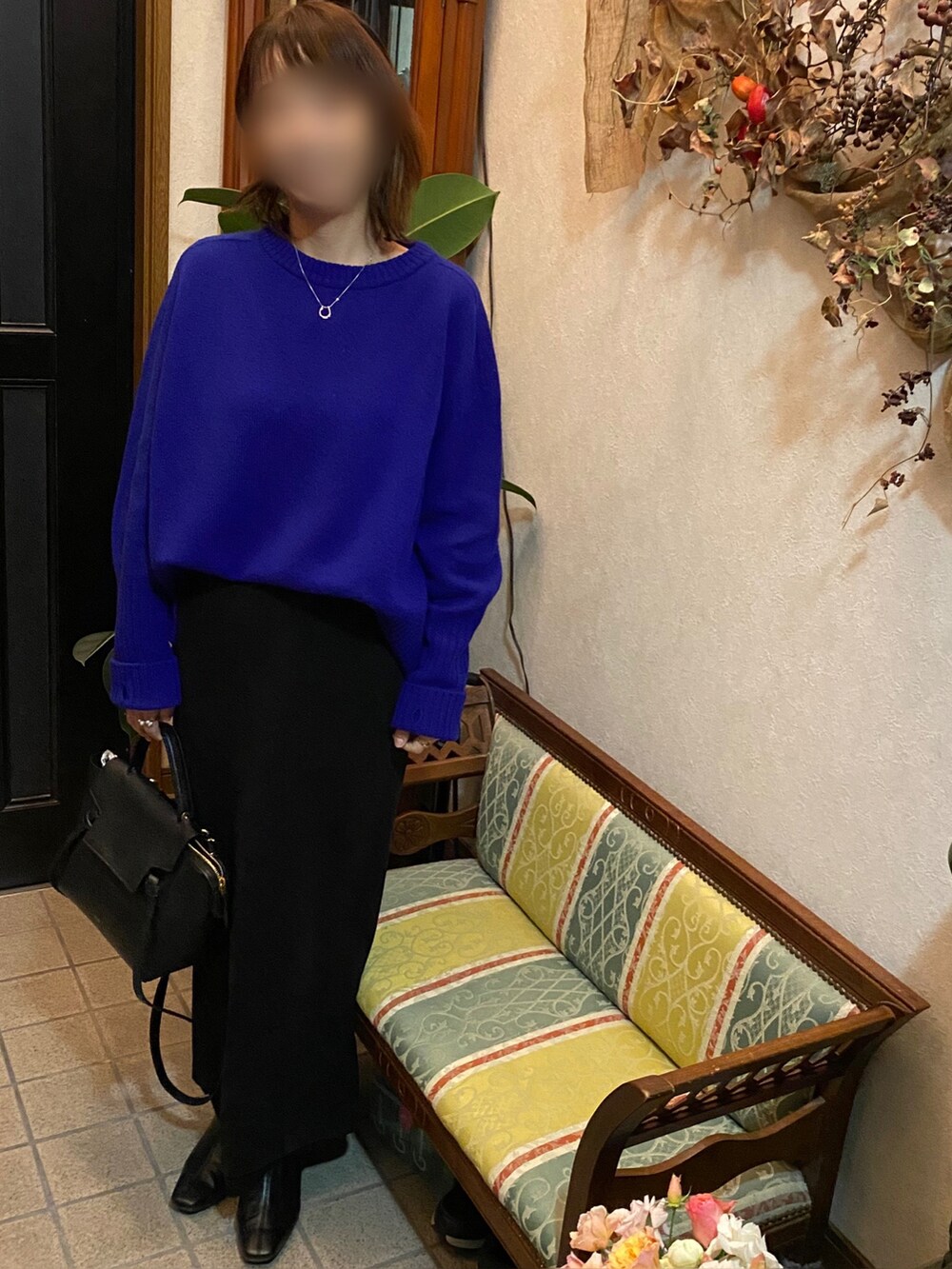 ブルー系のニット/セーター、ブラック系のスカート、ブラック系のブーツを着用したレディースの冬コーディネートの2枚目の写真