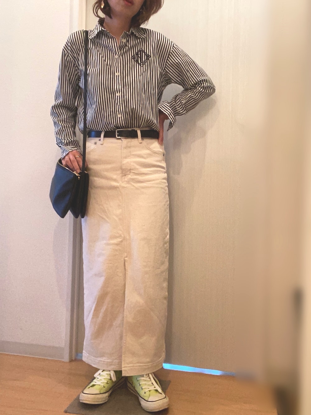 ブラック系のシャツ/ブラウス、ホワイト系のデニムスカート、イエロー系のスニーカーを着用したレディースの春コーディネートの2枚目の写真