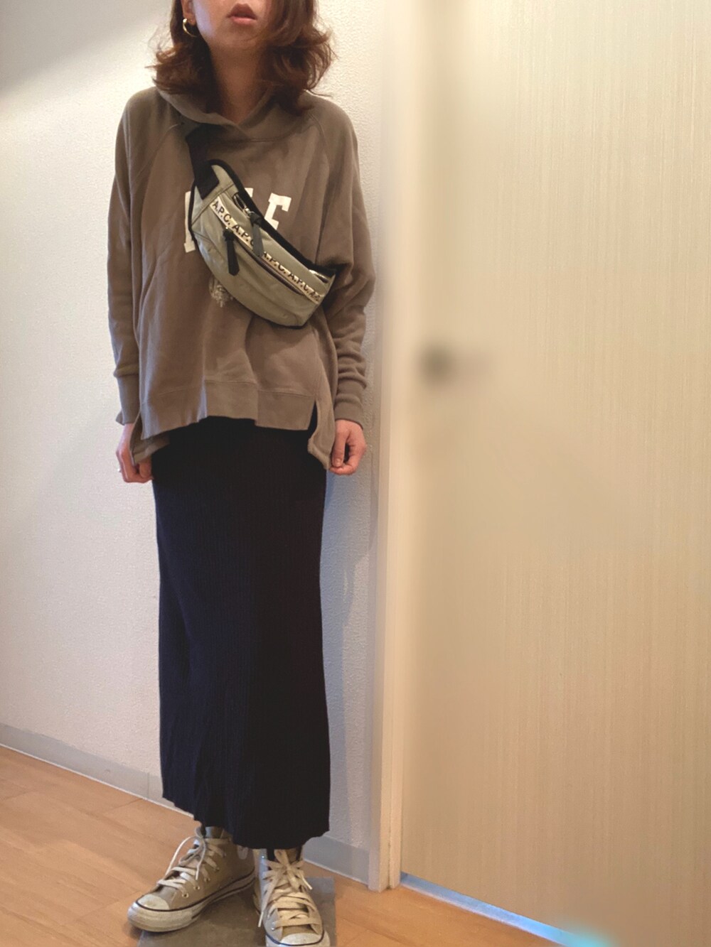 グリーン系のパーカー、ブラック系のスカート、グレー系のボディバッグ/ウエストポーチを着用したレディースの春コーディネートの2枚目の写真