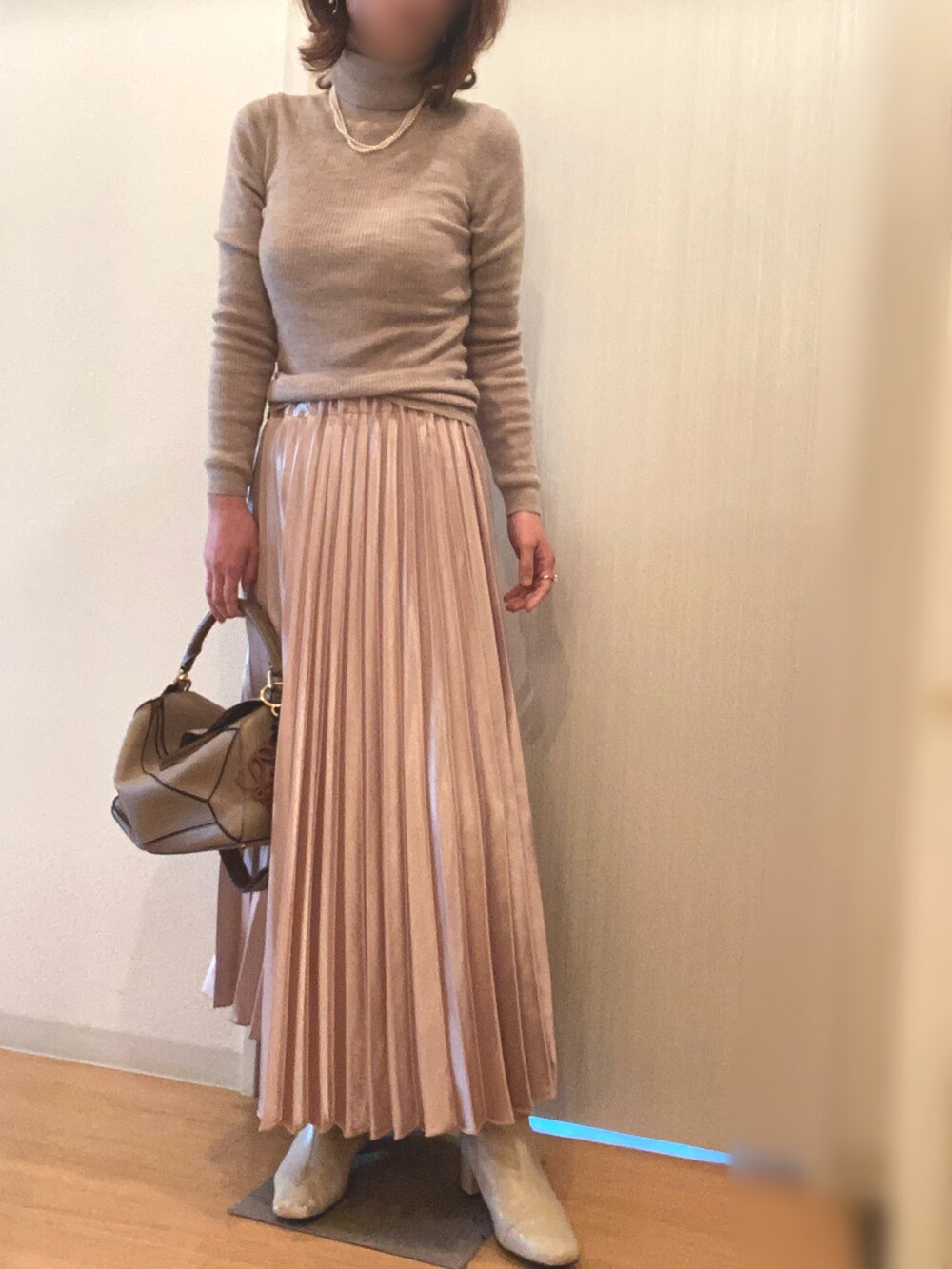 ベージュ系のスカート、ベージュ系のブーツ、ブラック系のカーディガン/ボレロを着用したレディースの春コーディネートの2枚目の写真