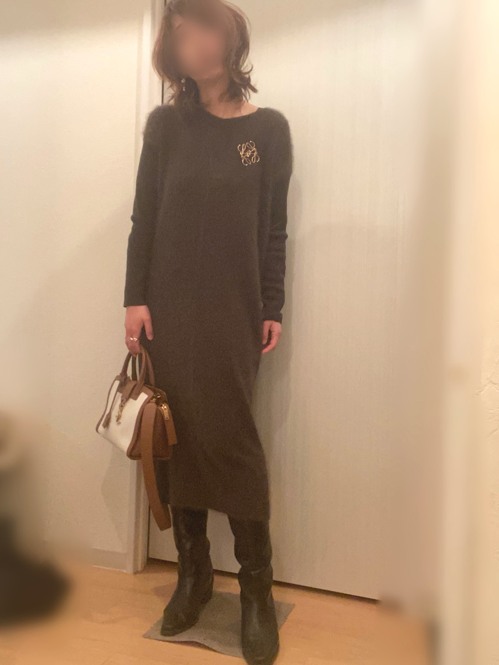 ブラック系のステンカラーコート、グリーン系のワンピース、ブラック系のブーツを着用したレディースの冬コーディネートの2枚目の写真