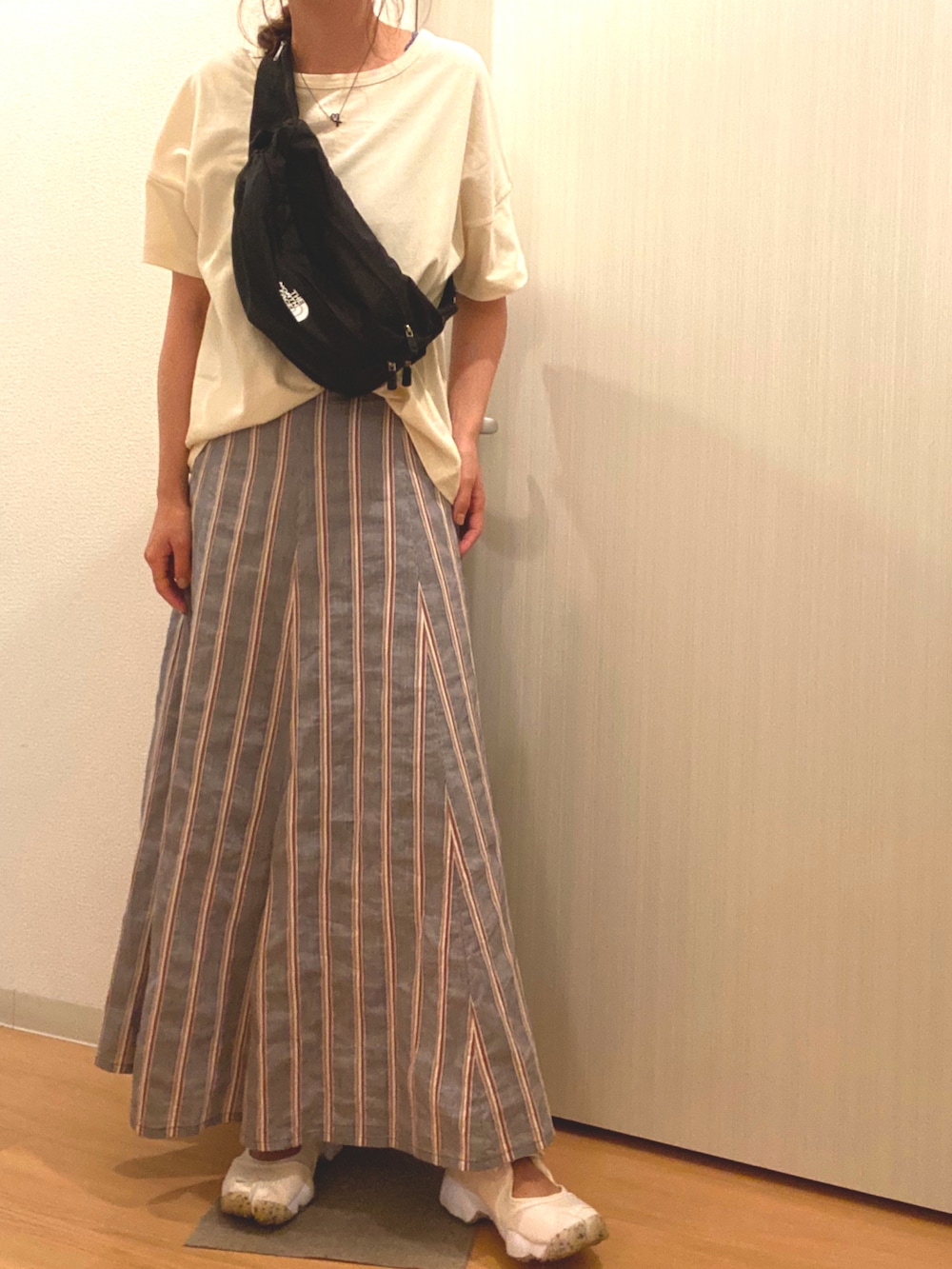 ベージュ系のTシャツ/カットソー、ブラック系のスカート、ホワイト系のスニーカーを着用したレディースの夏コーディネートの3枚目の写真