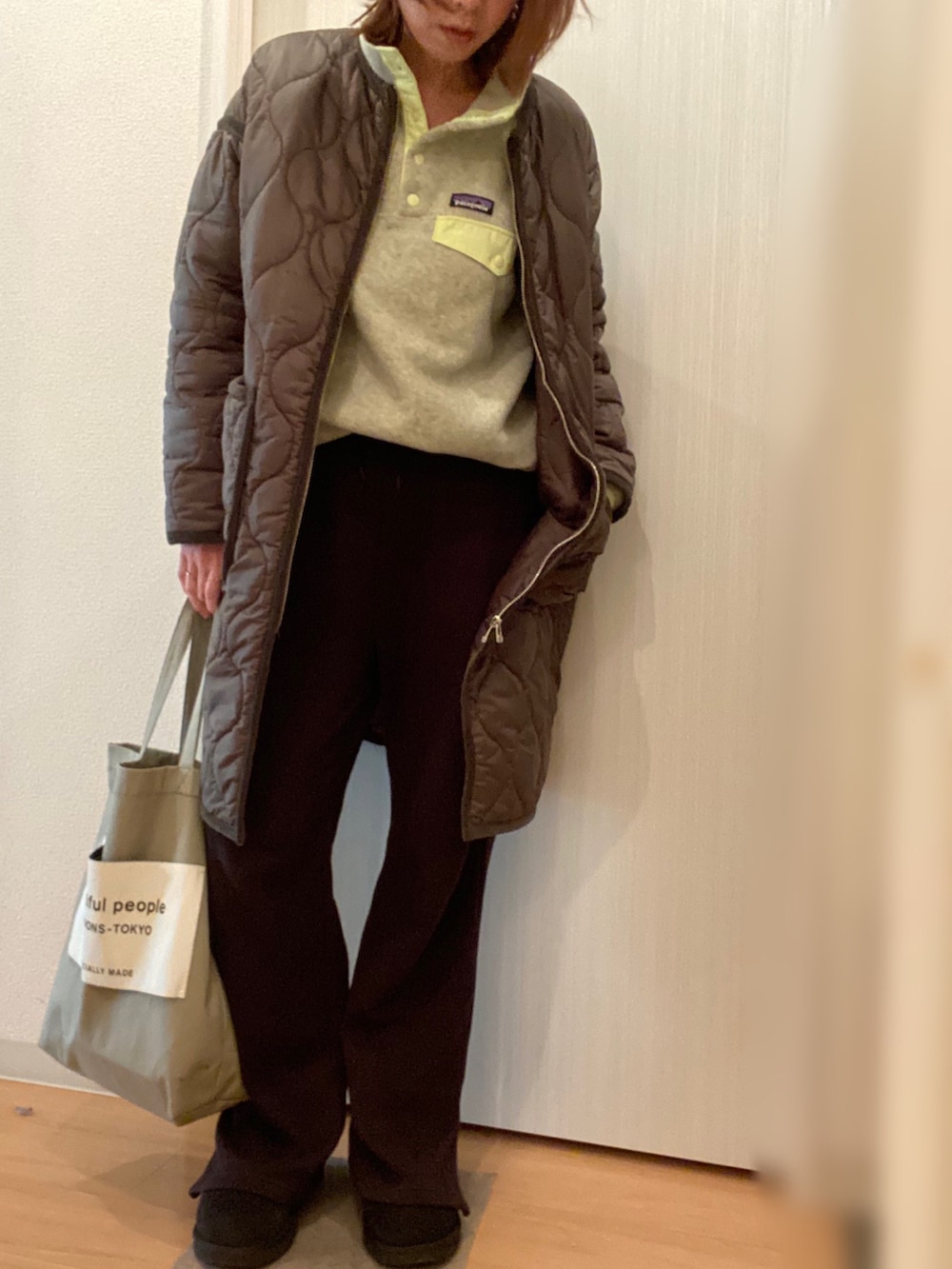 イエロー系のトップス、ブラック系のその他パンツ、グリーン系のトートバッグを着用したレディースの冬コーディネートの2枚目の写真