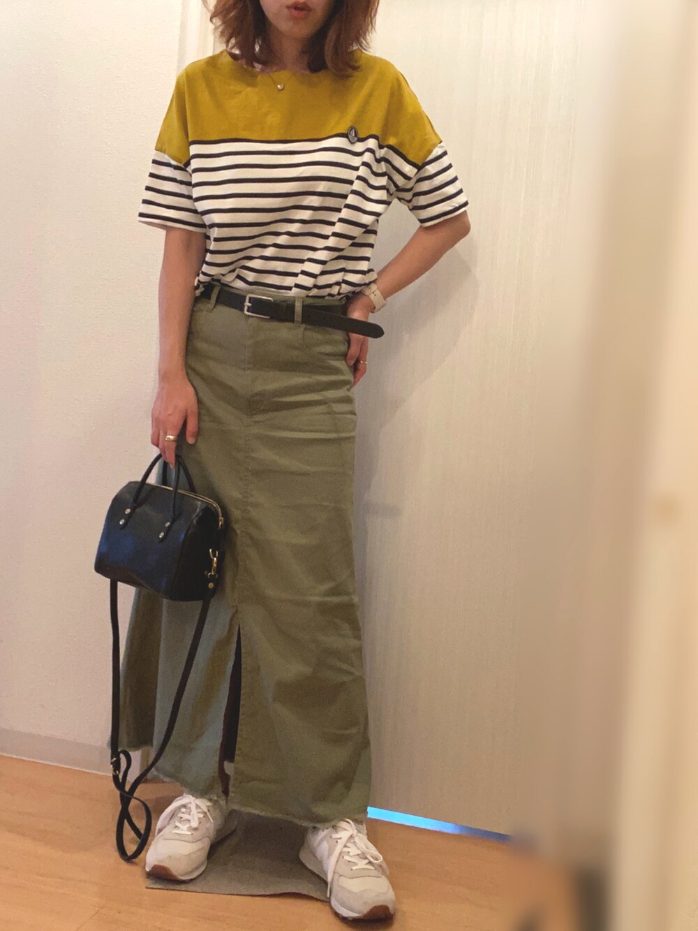 イエロー系のTシャツ/カットソー、グリーン系のスカート、グレー系のスニーカーを着用したレディースの秋コーディネートの2枚目の写真