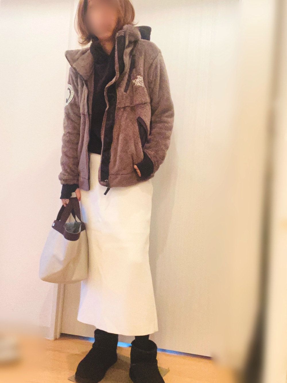 ブラック系のブルゾン、ホワイト系のスカート、ブラック系のブーツを着用したレディースの冬コーディネートの2枚目の写真