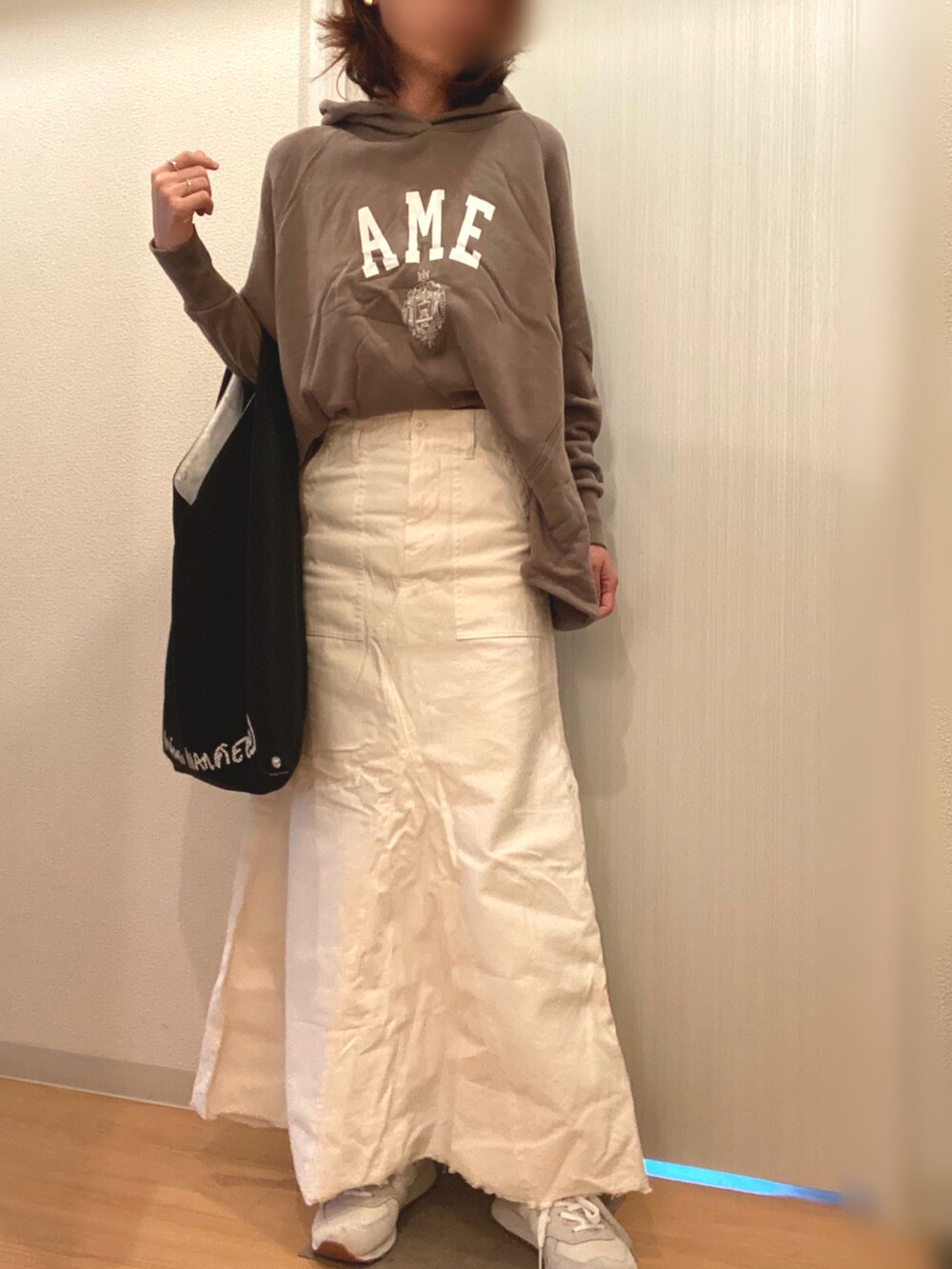 グリーン系のパーカー、ホワイト系のスカート、ブラック系のハンドバッグを着用したレディースの秋コーディネートの3枚目の写真