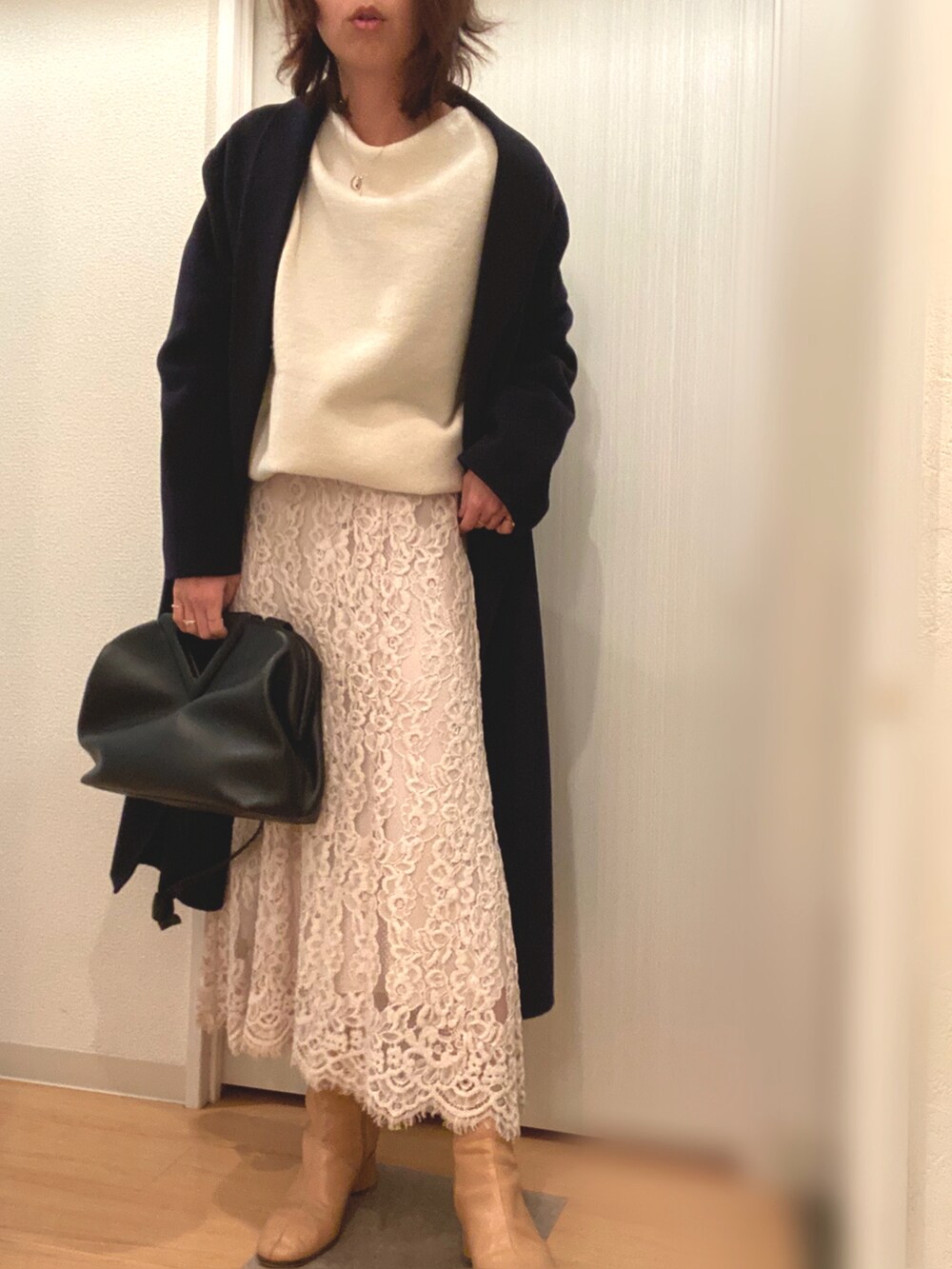 ホワイト系のニット/セーター、ベージュ系のスカート、ベージュ系のブーツを着用したレディースの冬コーディネートの3枚目の写真