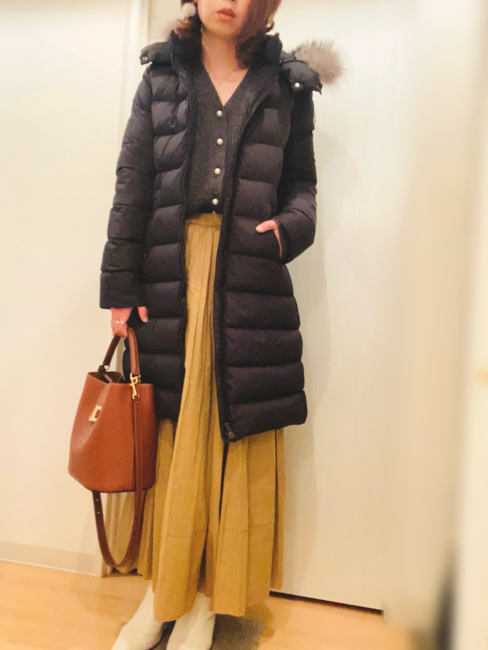 グレー系のカーディガン/ボレロ、イエロー系のスカート、ホワイト系のブーツを着用したレディースの冬コーディネートの2枚目の写真