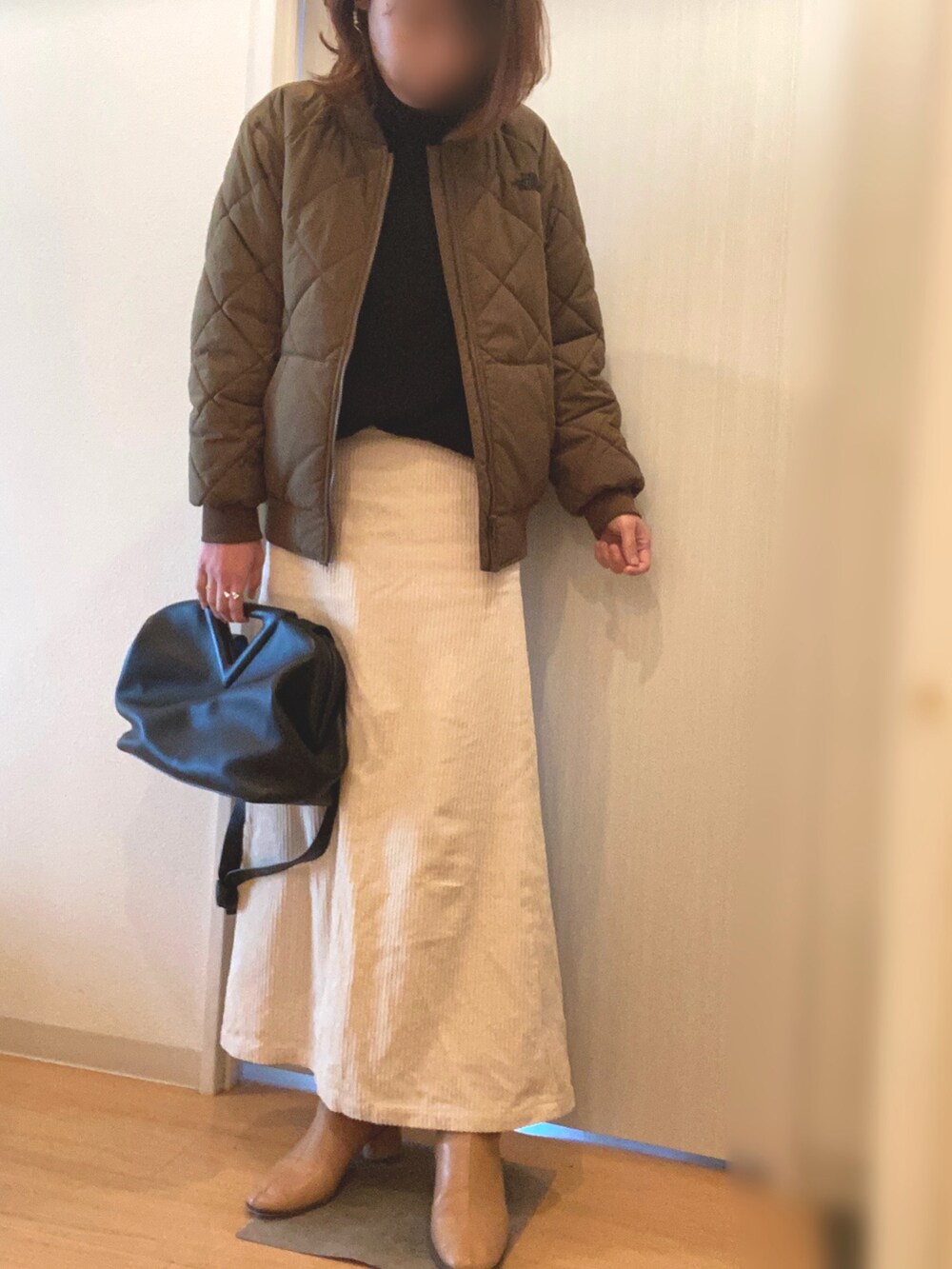 グリーン系のジャケット/アウター、ブラック系のニット/セーター、ホワイト系のスカートを着用したレディースの冬コーディネートの2枚目の写真