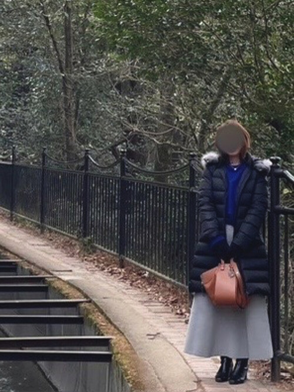 ブルー系のニット/セーター、グレー系のスカート、ブラック系のダウンジャケット/コートを着用したレディースの冬コーディネートの2枚目の写真