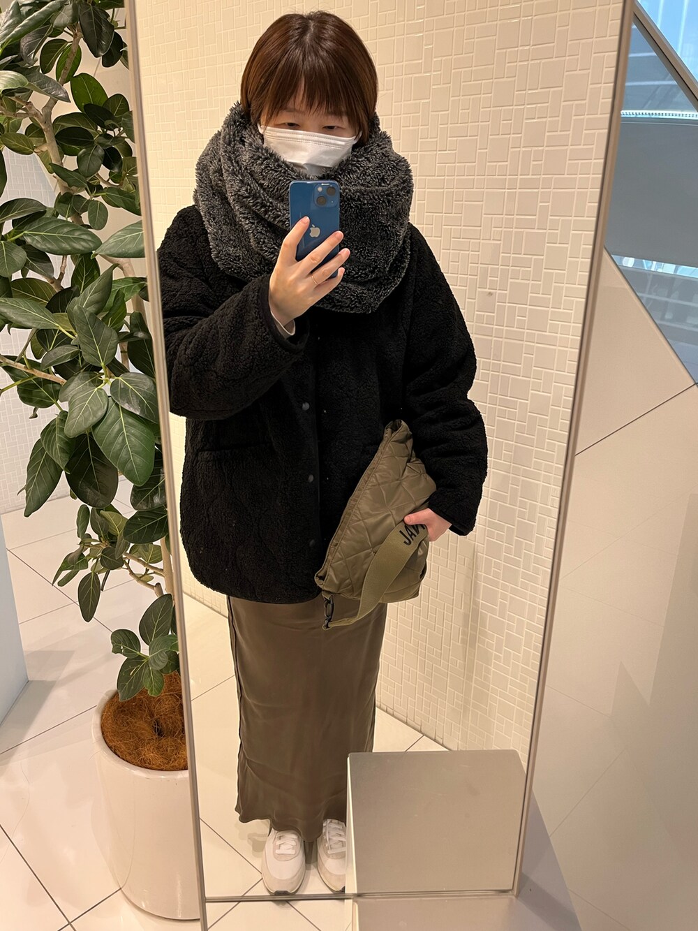 グリーン系のショルダーバッグ、ホワイト系のスニーカーを着用したレディースの冬コーディネートの2枚目の写真