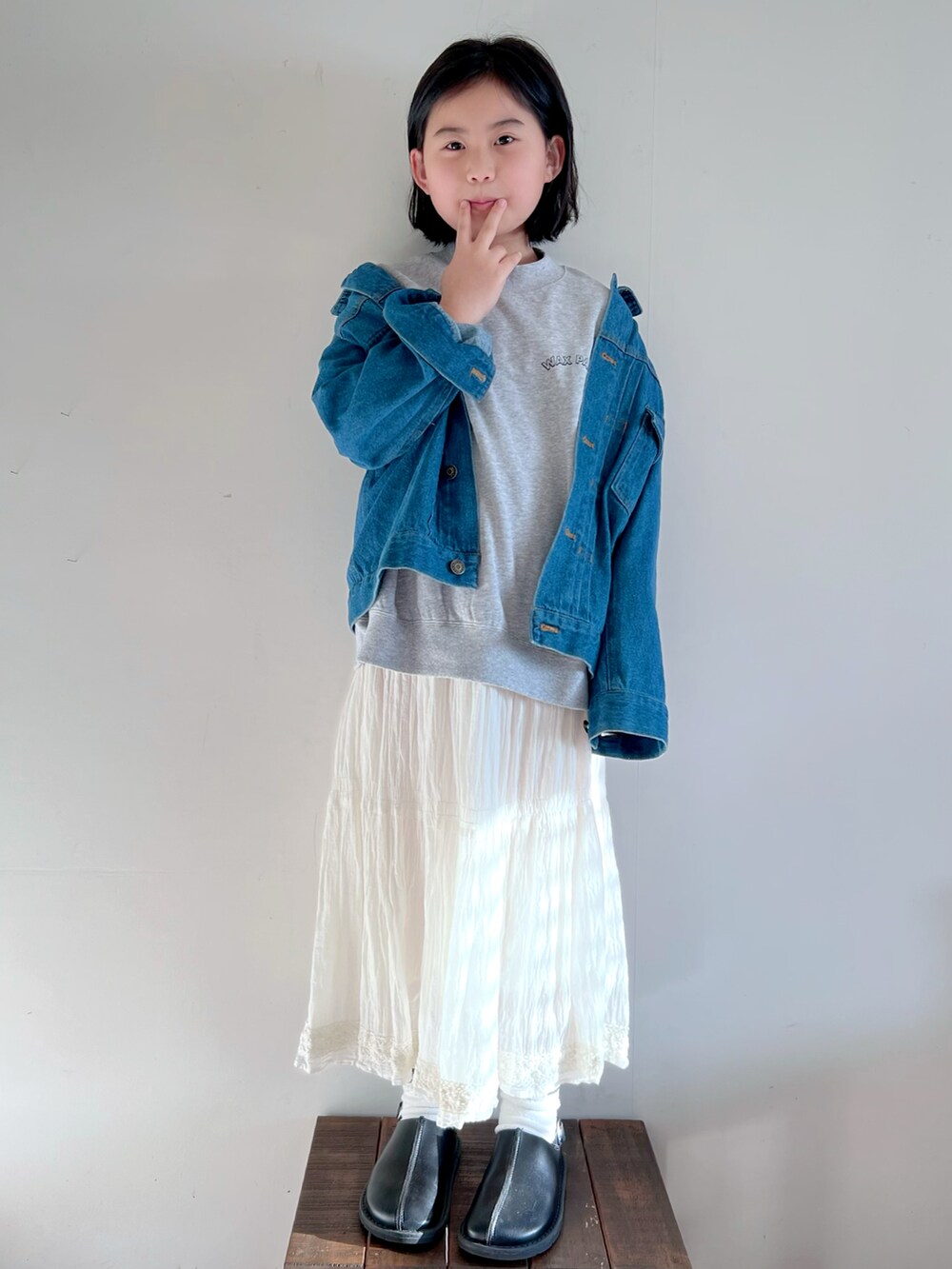ブルー系のデニムジャケット、グレー系のTシャツ/カットソー、ホワイト系のスカートを着用したキッズの春コーディネートの2枚目の写真