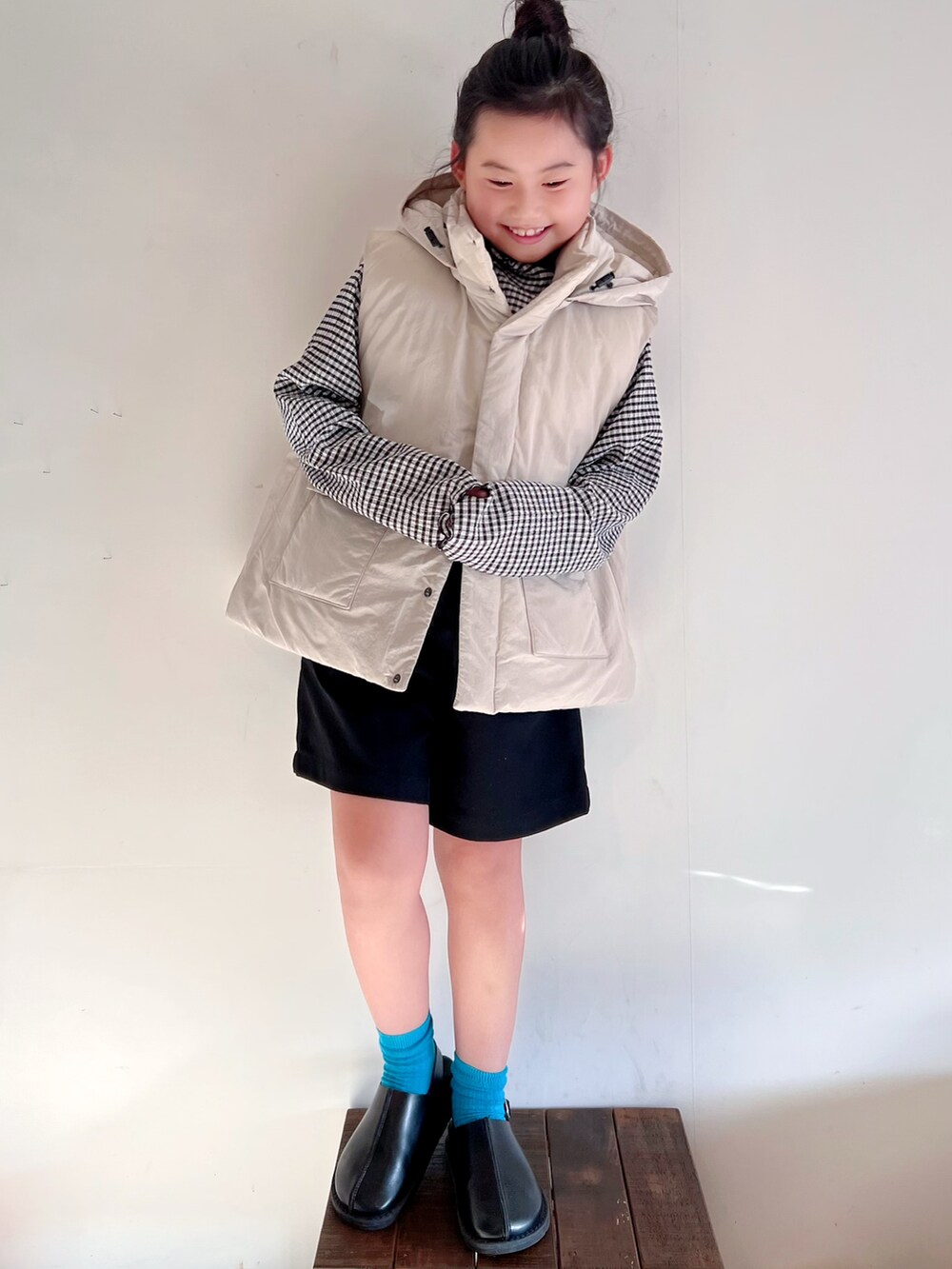 ホワイト系のダウンベスト、ブラック系のTシャツ/カットソー、ブラック系のパンツを着用したキッズの秋コーディネートの2枚目の写真