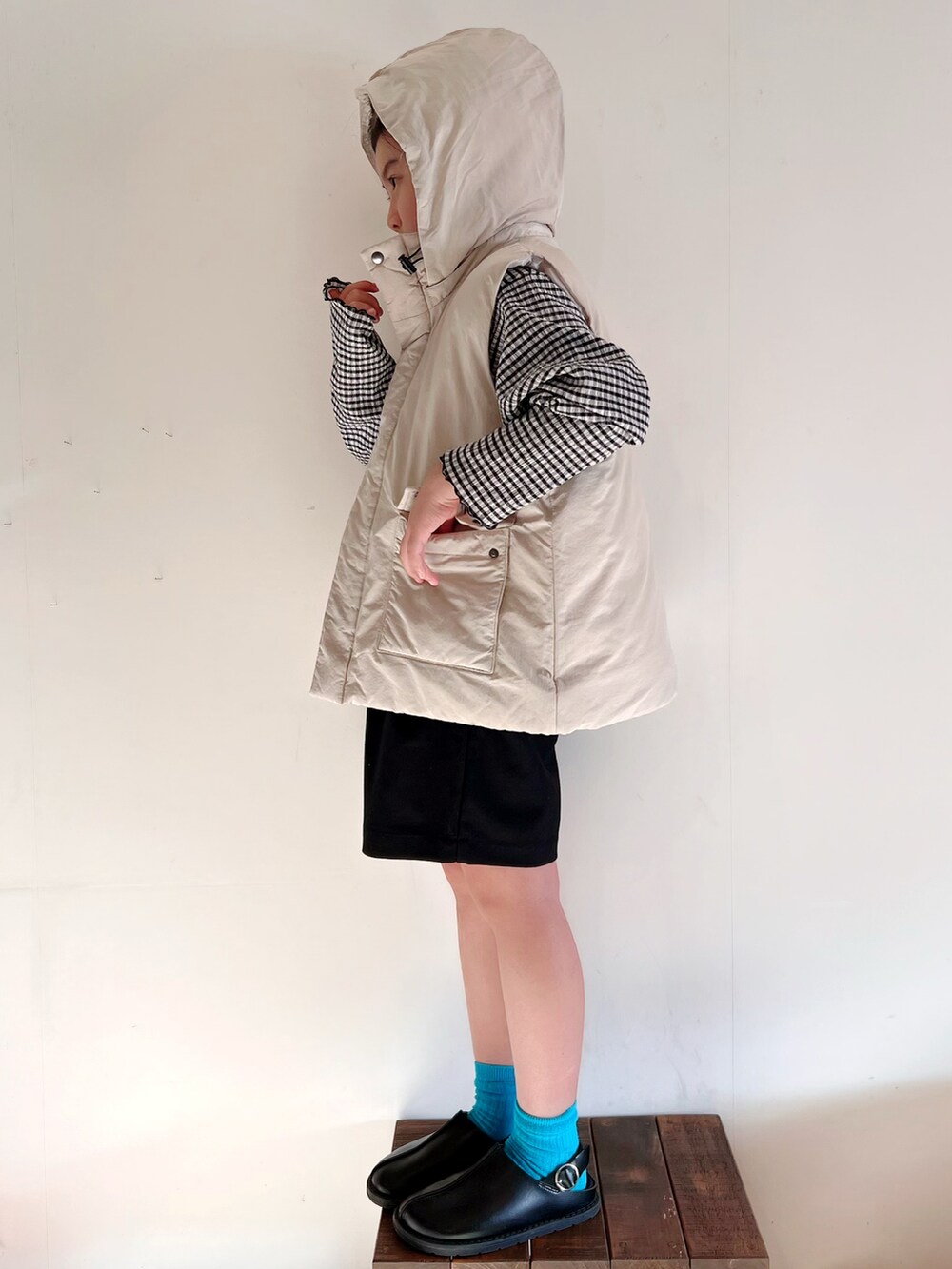 ホワイト系のダウンベスト、ブラック系のTシャツ/カットソー、ブラック系のパンツを着用したキッズの秋コーディネートの3枚目の写真