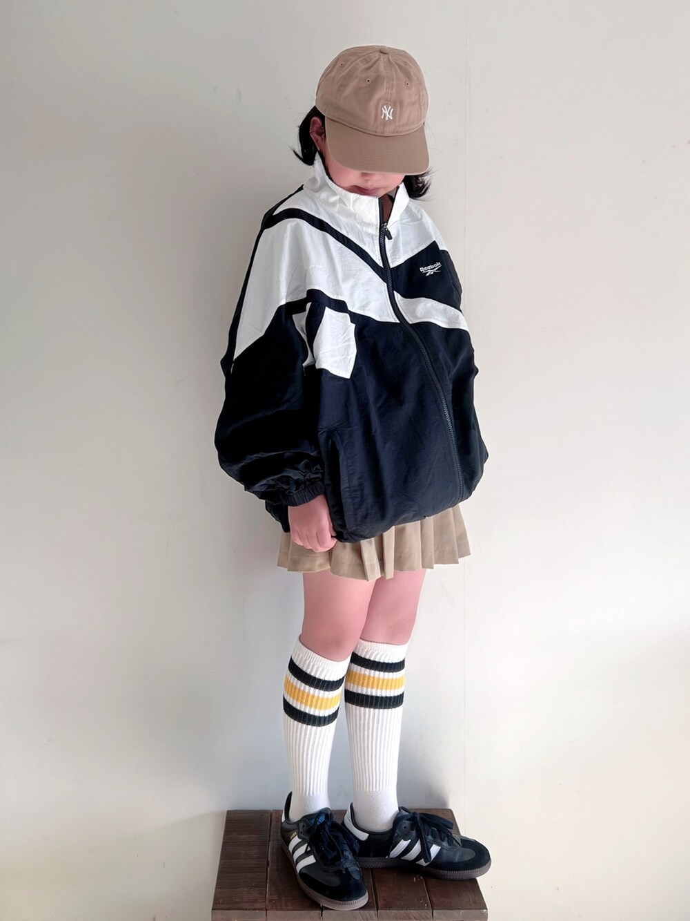 「春のおしゃ見えテクニック、春服みてみて、お出かけコーデ、プリーツスカート、春アウター、トラックジャケット、リーボック(Reebok)、ラインソックス、adidas、samba、キャップ、スポーツミックス、スニーカーコーデ、休日スタイル」｜「Reebokの【Reebok/リーボック】ナイロンベクターJK/ビッグロゴナイロントラックジャケットブルゾン（ブルゾン、ブラック系）」を使った、bow-changさん（キッズ・130cm）の春コーディネートの2枚目の写真