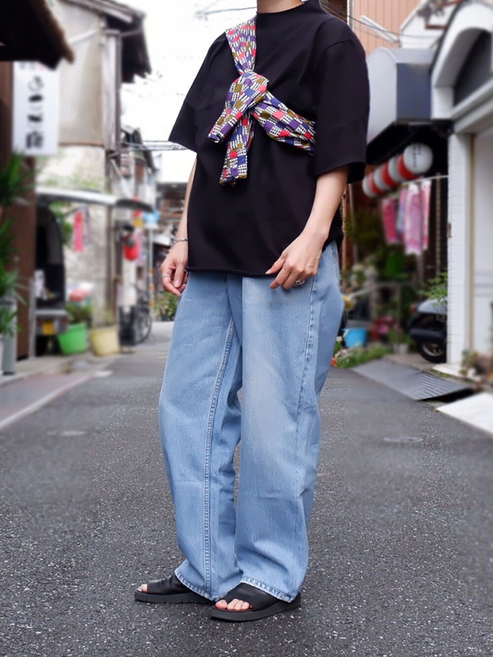 ブルー系のデニムパンツ、ブラック系のサンダル、ブラック系のTシャツ/カットソーを着用したレディースの春コーディネートの2枚目の写真