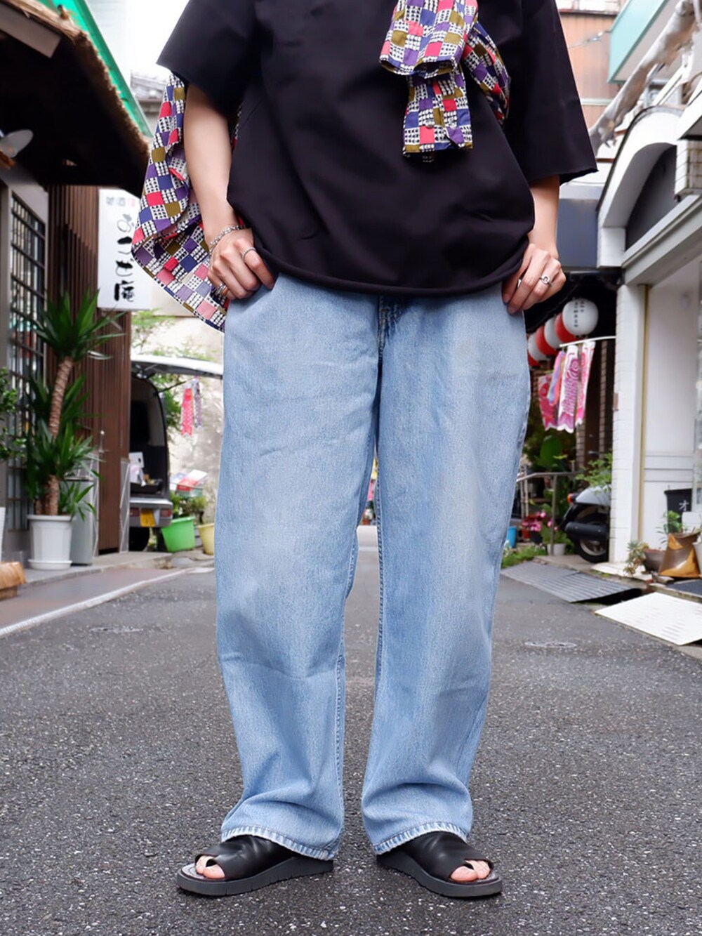 ブルー系のデニムパンツ、ブラック系のサンダル、ブラック系のTシャツ/カットソーを着用したレディースの春コーディネートの3枚目の写真