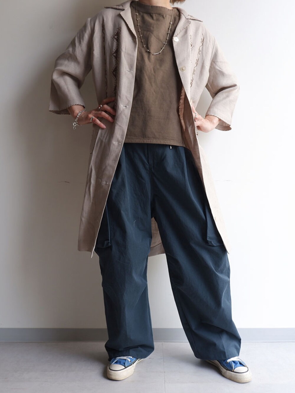 ブルー系のカーゴパンツ、ベージュ系のステンカラーコート、ベージュ系のTシャツ/カットソーを着用したレディースの春コーディネートの2枚目の写真