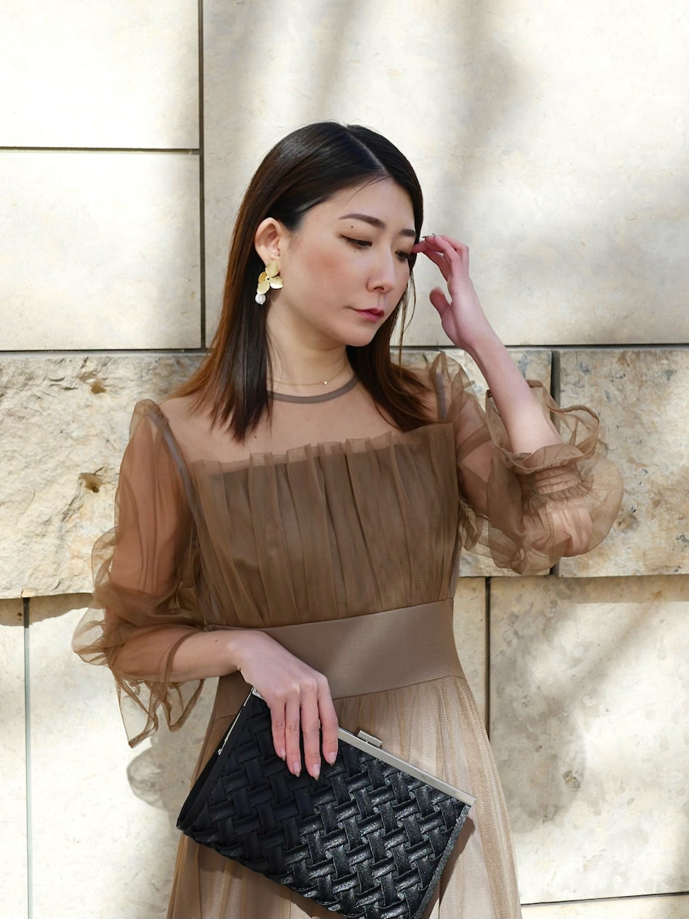 ブラウン系のドレス、ブラック系のクラッチバッグ、ブラック系のブーツを着用したレディースの春コーディネートの3枚目の写真