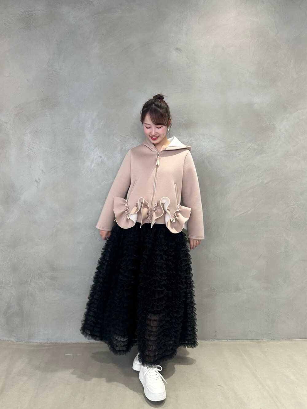 ベージュ系のパーカー、ブラック系のスカートを着用したレディースの冬コーディネートの2枚目の写真