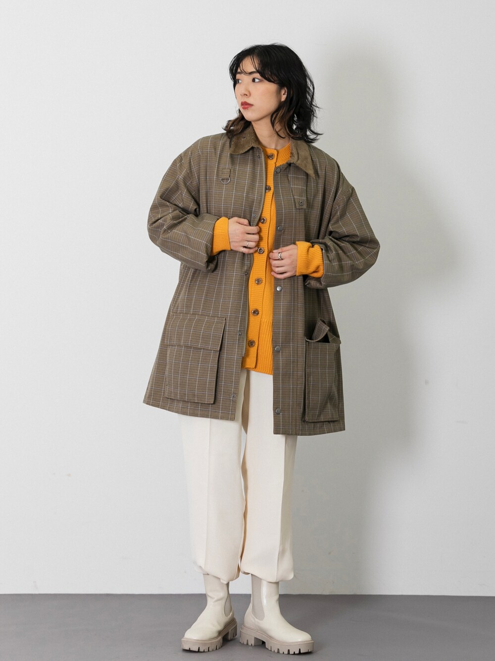 ベージュ系のミリタリージャケット、オレンジ系のカーディガン/ボレロ、ホワイト系のスラックスを着用したレディースの秋コーディネートの2枚目の写真