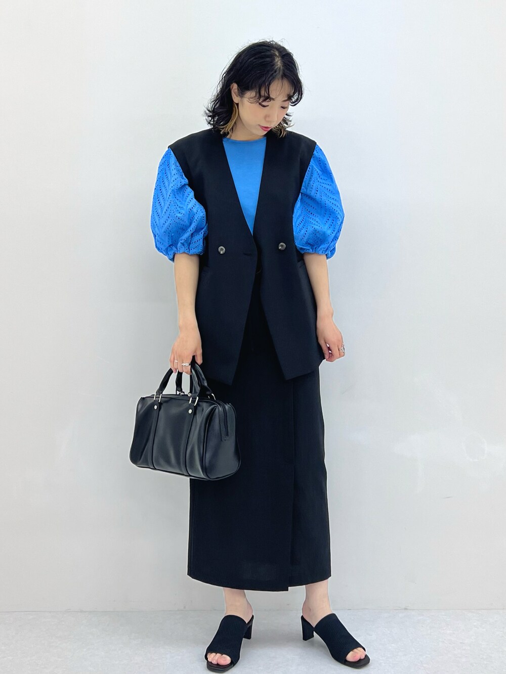 ブラック系のその他アウター、ブラック系のスカート、ブラック系のボストンバッグを着用したレディースの春コーディネートの2枚目の写真