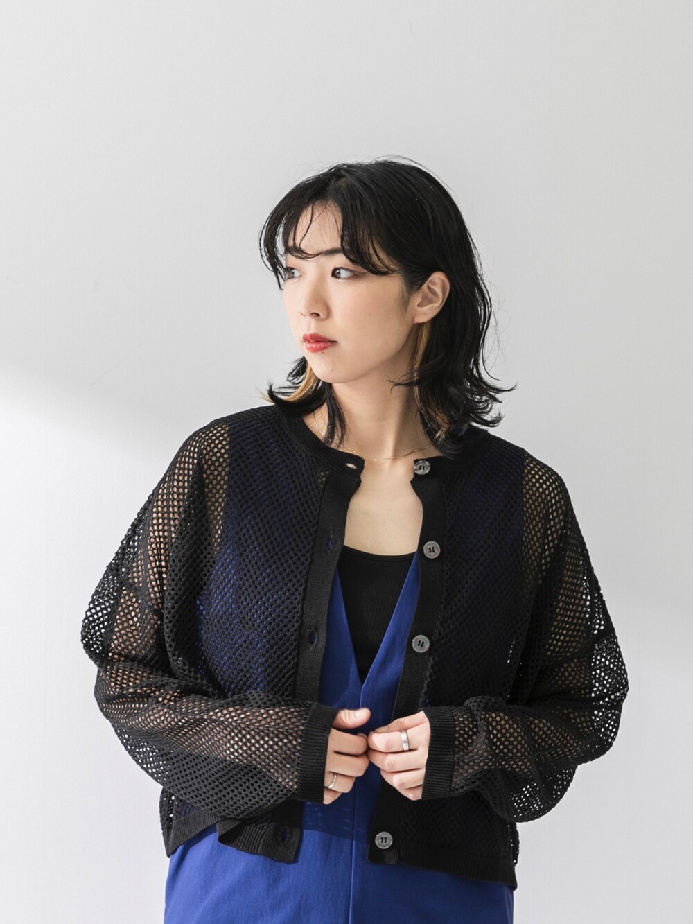 ブラック系のカーディガン/ボレロ、ブルー系のジャンパースカート、ブラック系のハンドバッグを着用したレディースの夏コーディネートの3枚目の写真