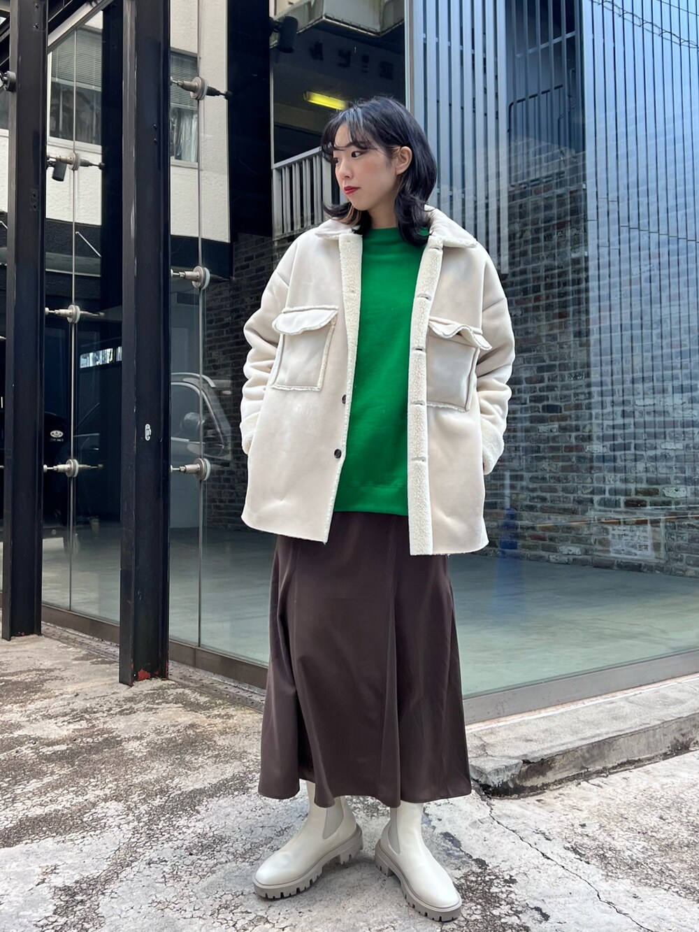 ベージュ系のムートンコート、グリーン系のスウェット、ホワイト系のブーツを着用したレディースの冬コーディネートの2枚目の写真