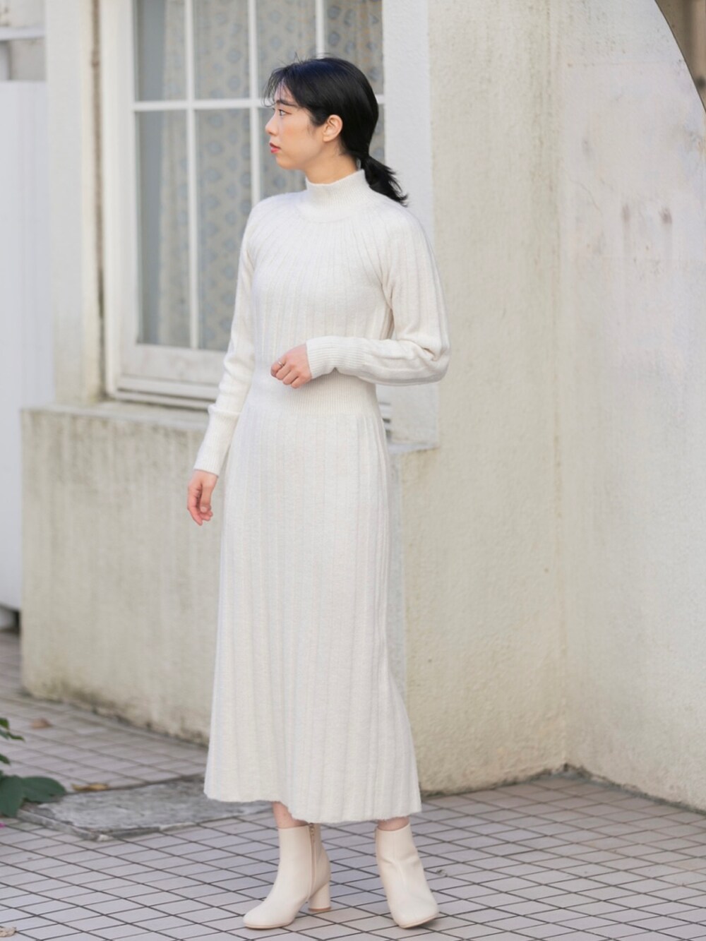 ホワイト系のナイロンジャケット、ホワイト系のワンピース、ホワイト系のブーツを着用したレディースの冬コーディネートの4枚目の写真