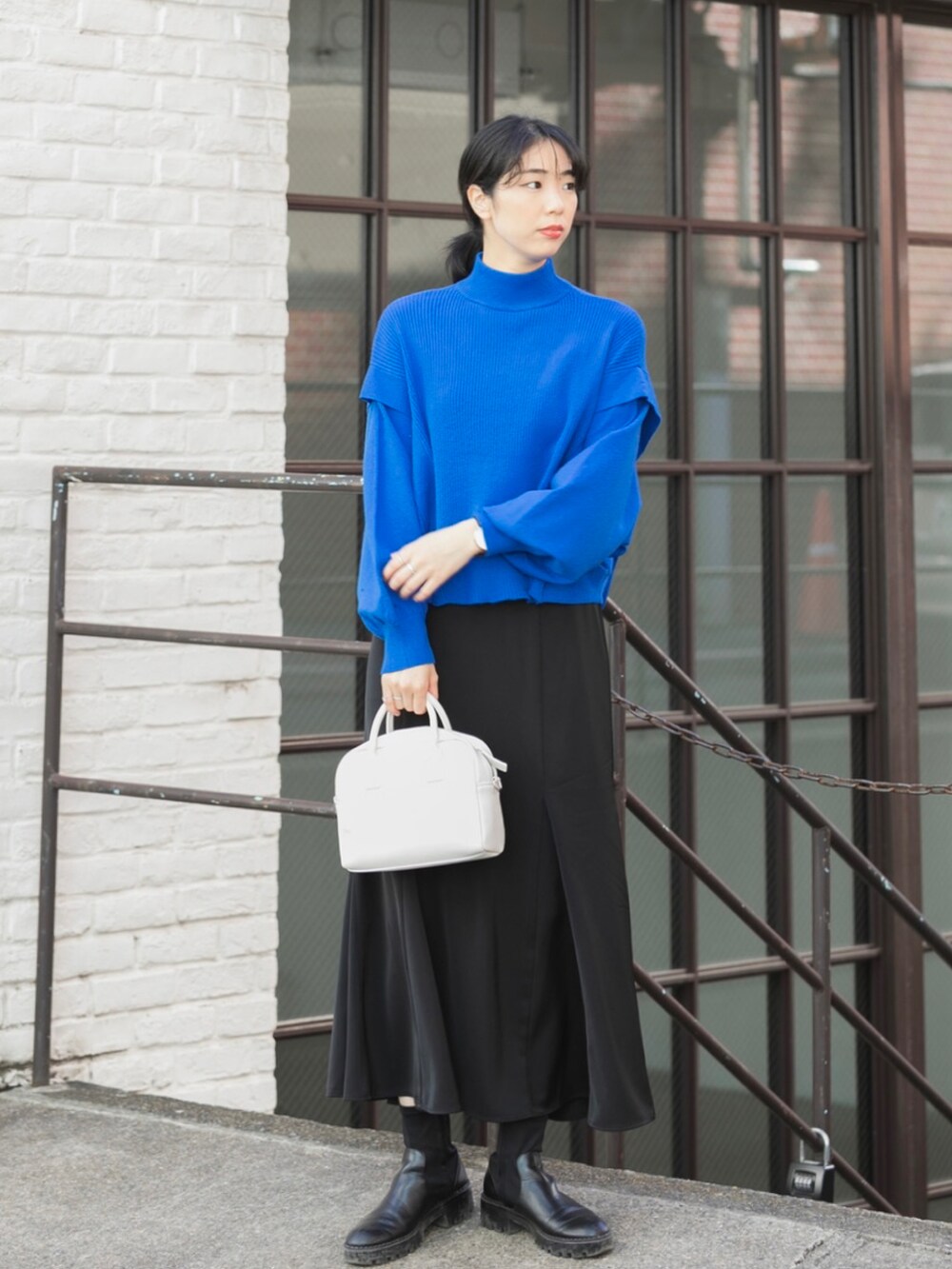 ブラック系のブルゾン、ブルー系のニット/セーター、ホワイト系のボストンバッグを着用したレディースの秋コーディネートの4枚目の写真