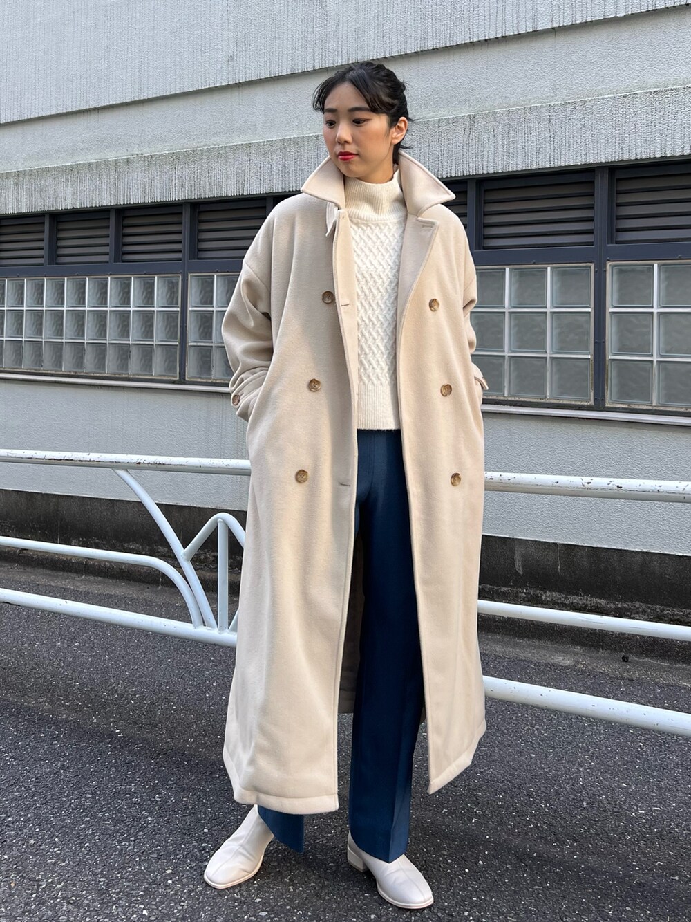 ベージュ系のステンカラーコート、ホワイト系のベスト、ホワイト系のニット/セーターを着用したレディースの秋コーディネートの2枚目の写真