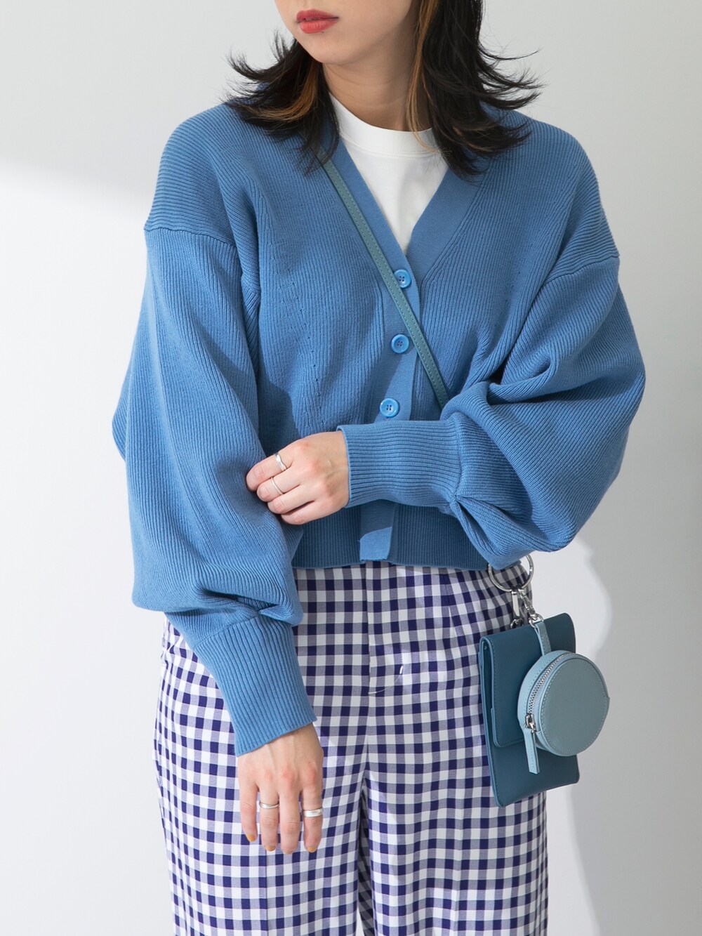 ブルー系のカーディガン/ボレロ、ブルー系のショルダーバッグ、ホワイト系のTシャツ/カットソーを着用したレディースの冬コーディネートの3枚目の写真