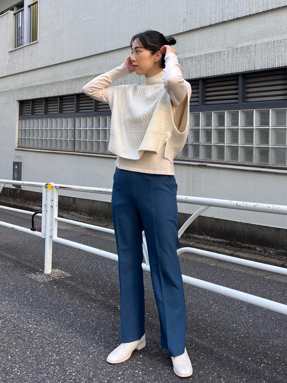 ベージュ系のステンカラーコート、ホワイト系のベスト、ホワイト系のニット/セーターを着用したレディースの秋コーディネートの4枚目の写真