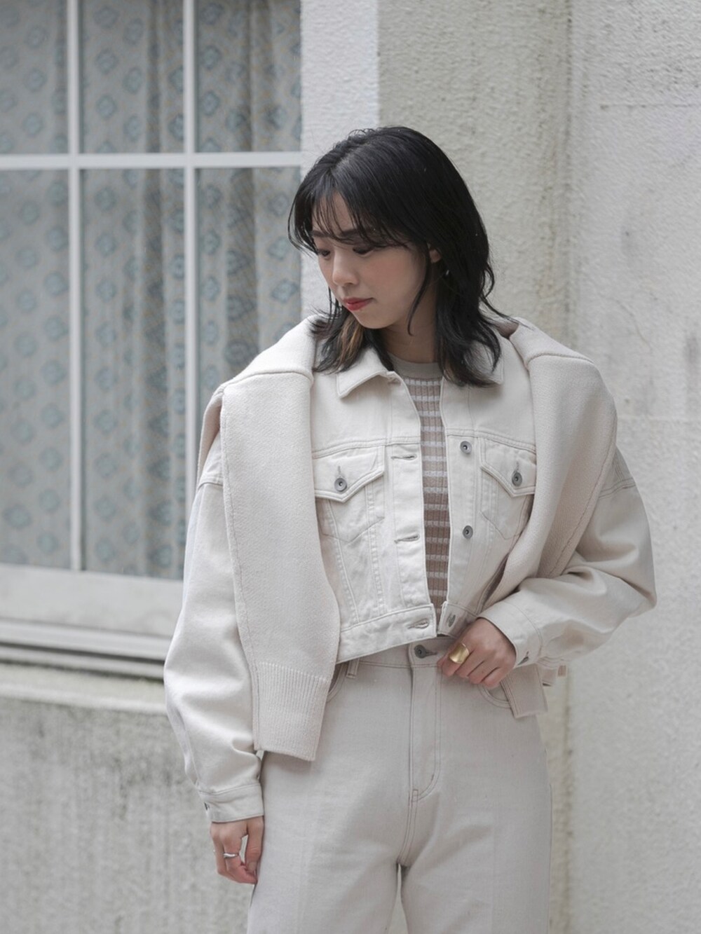 ホワイト系のデニムジャケット、ホワイト系のデニムパンツ、ベージュ系のニット/セーターを着用したレディースの冬コーディネートの2枚目の写真