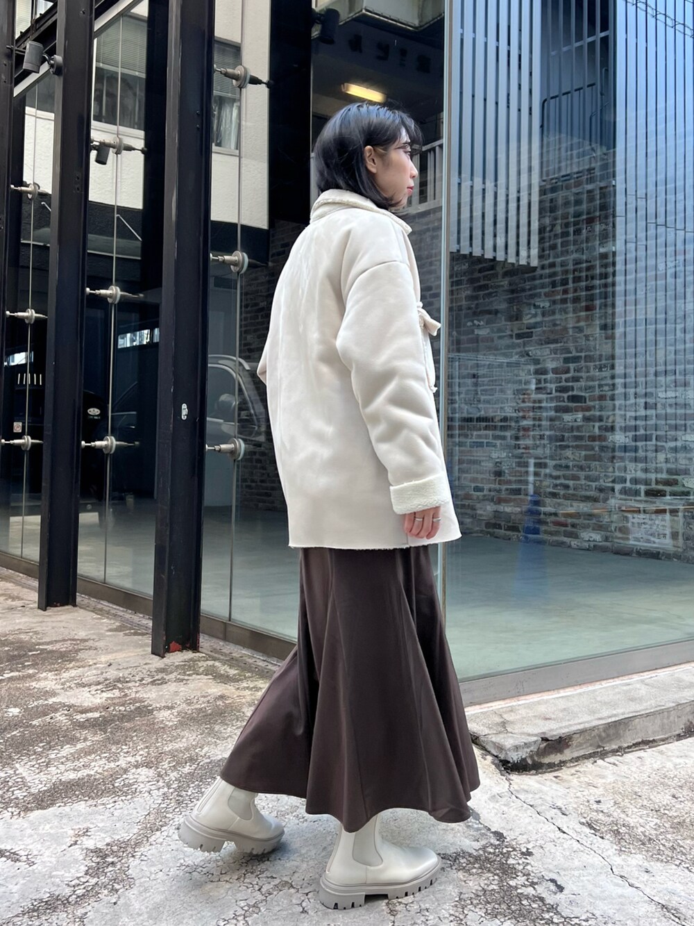 ベージュ系のムートンコート、グリーン系のスウェット、ホワイト系のブーツを着用したレディースの冬コーディネートの3枚目の写真