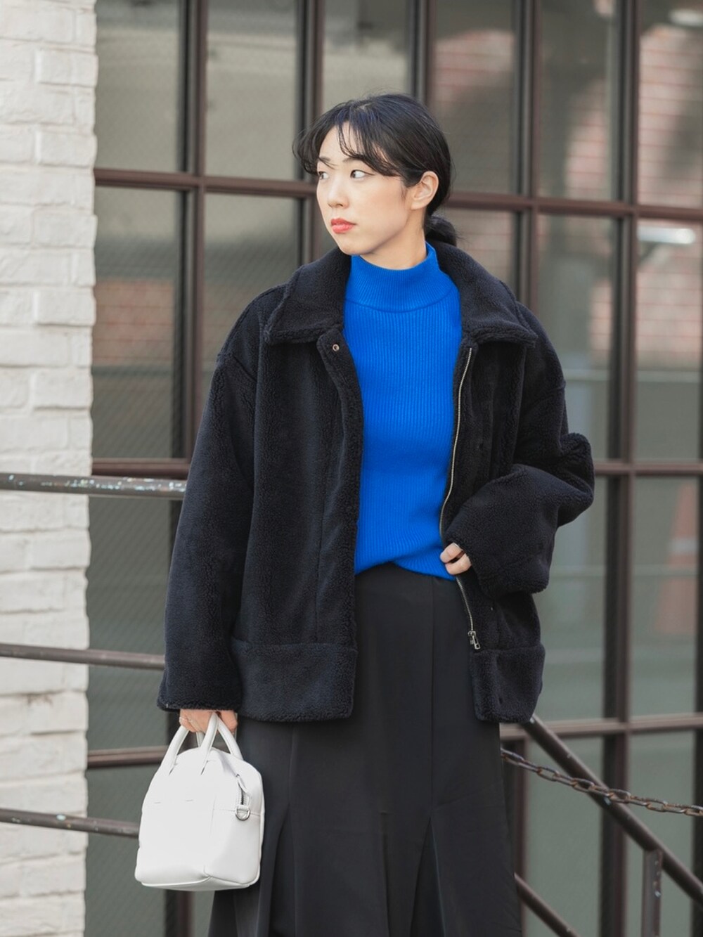 ブラック系のブルゾン、ブルー系のニット/セーター、ホワイト系のボストンバッグを着用したレディースの秋コーディネートの3枚目の写真