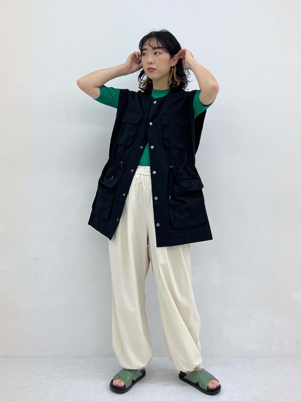 ホワイト系のその他パンツ、ブラック系のベスト、グリーン系のニット/セーターを着用したレディースの春コーディネートの2枚目の写真
