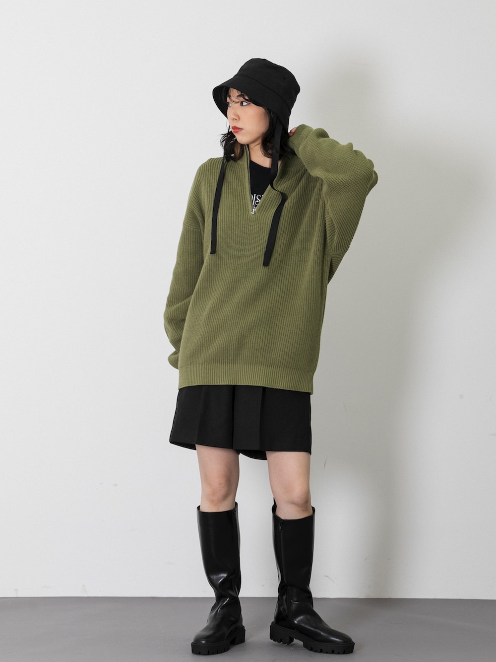 グリーン系のニット/セーター、ブラック系のスラックス、ブラック系のTシャツ/カットソーを着用したレディースの秋コーディネートの2枚目の写真