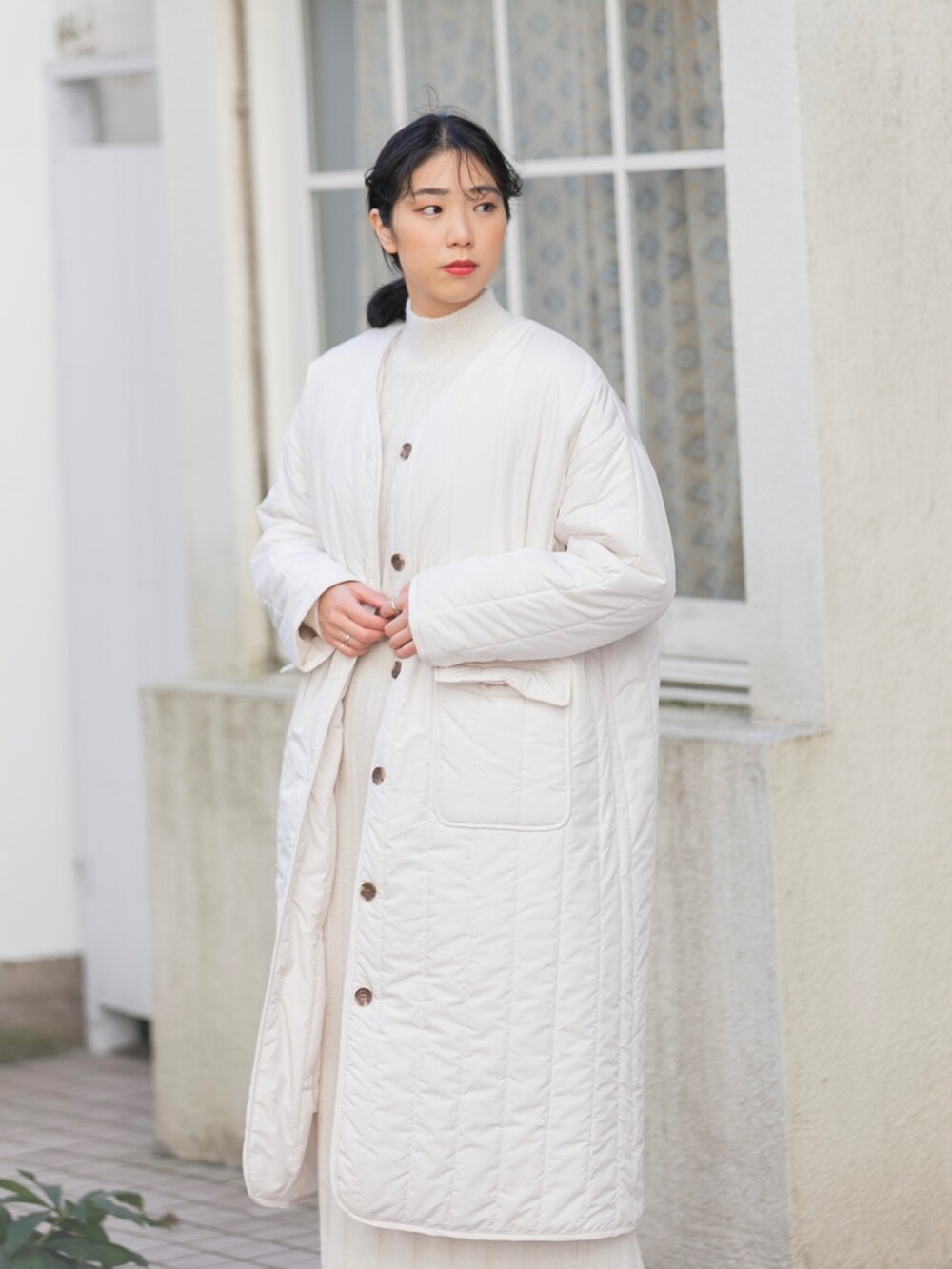 ホワイト系のナイロンジャケット、ホワイト系のワンピース、ホワイト系のブーツを着用したレディースの冬コーディネートの2枚目の写真