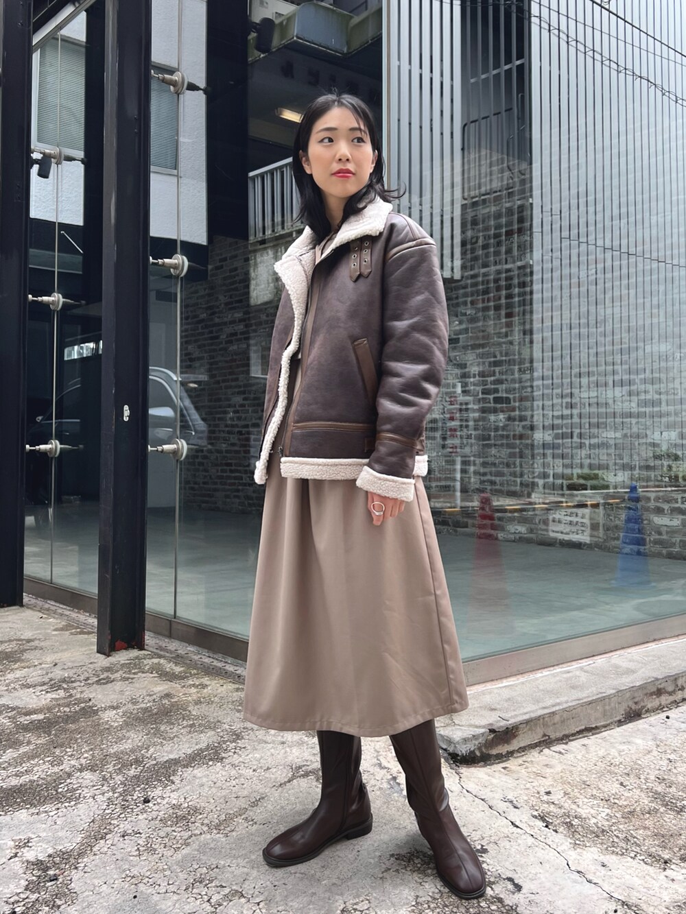 ベージュ系のワンピース、ブラウン系のブーツ、ブラウン系のブルゾンを着用したレディースの冬コーディネートの2枚目の写真