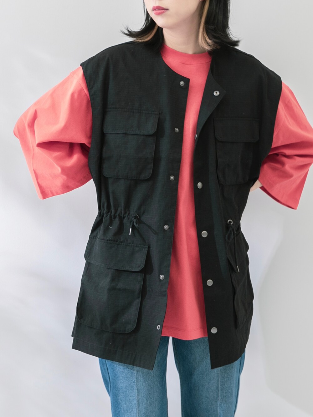 ブラック系のベスト、オレンジ系のTシャツ/カットソー、ブルー系のデニムパンツを着用したレディースの春コーディネートの4枚目の写真