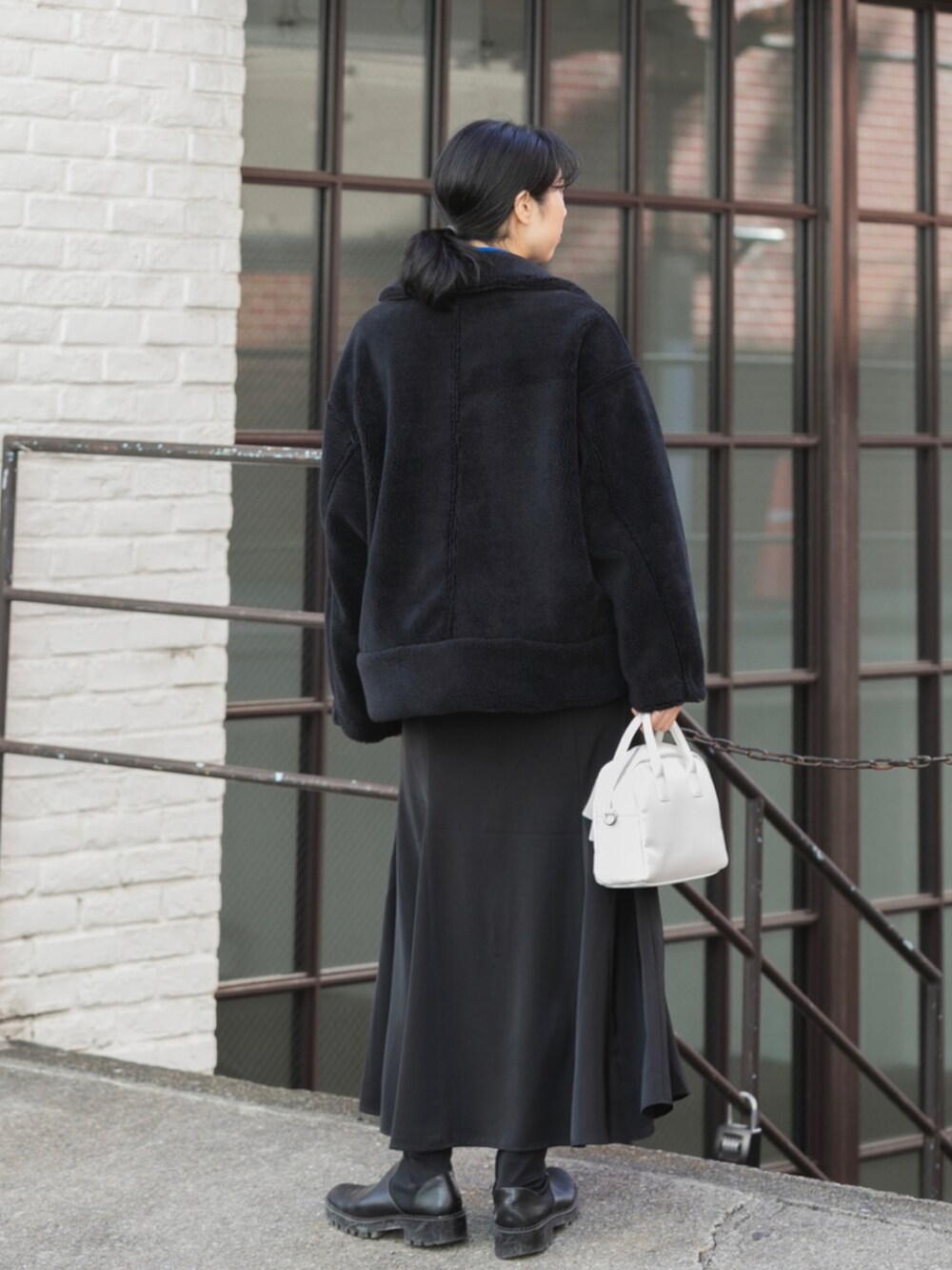 ブラック系のブルゾン、ブルー系のニット/セーター、ホワイト系のボストンバッグを着用したレディースの秋コーディネートの2枚目の写真