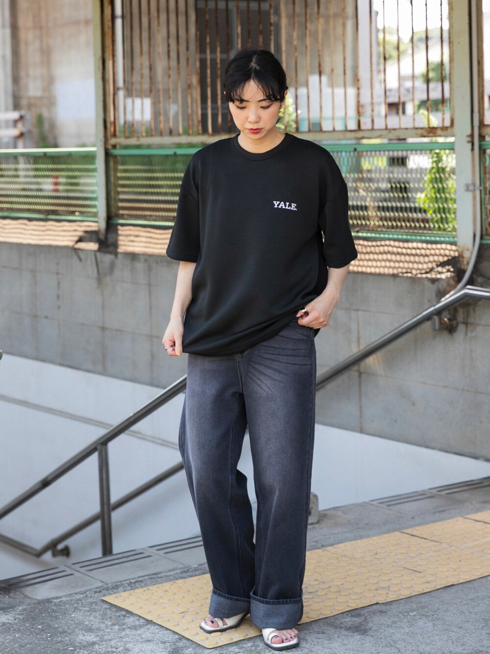ブラック系のTシャツ/カットソー、ブラック系のデニムパンツ、ホワイト系のサンダルを着用したレディースの夏コーディネートの2枚目の写真